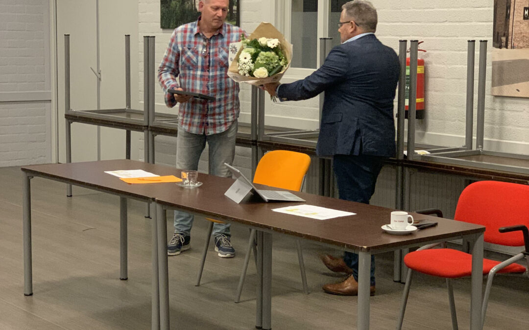 Voorzitter overhandigt een bos bloemen en ingelijst certificaat aan Arnoud Holl